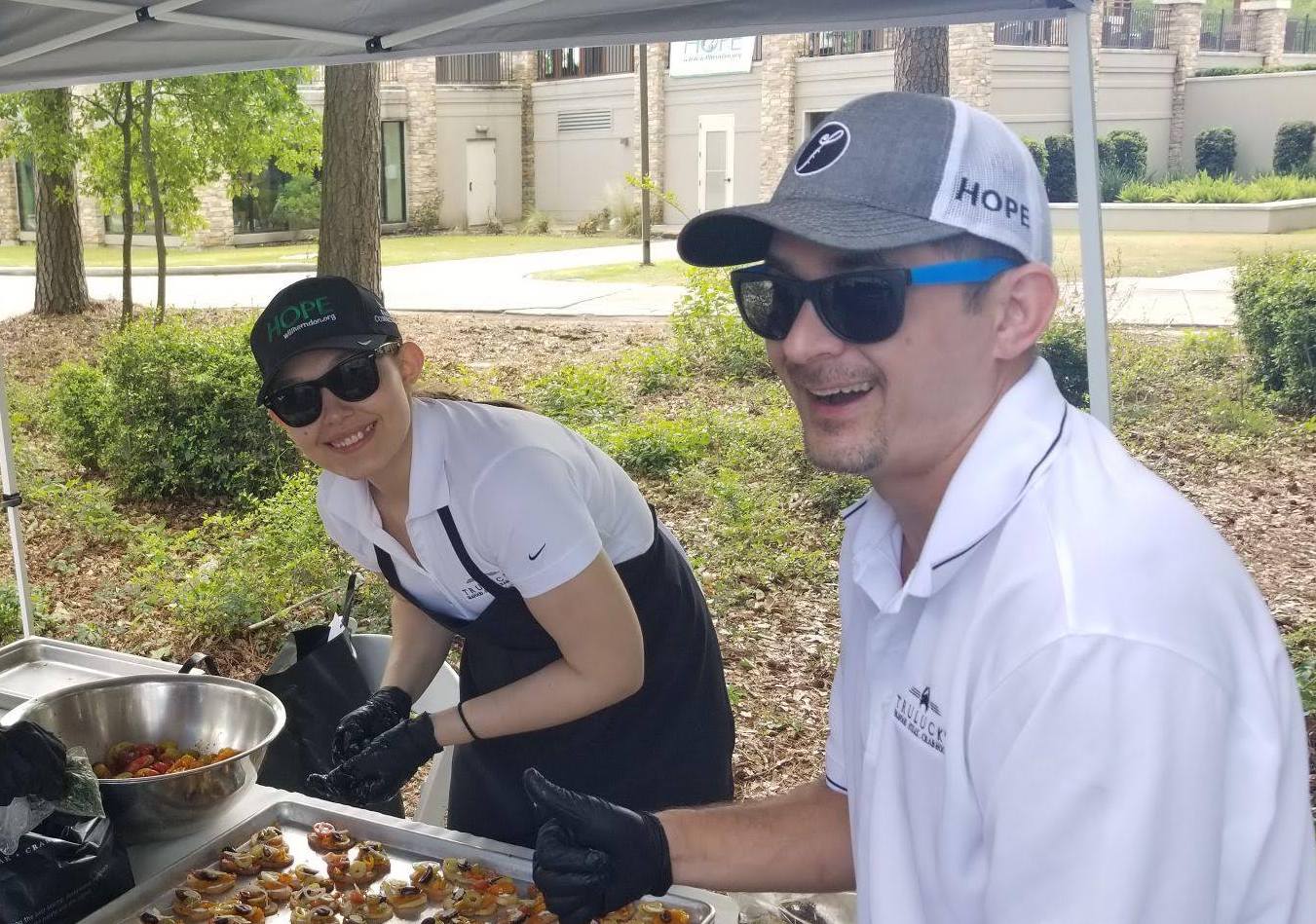 picture of Our staff smiling as they serve food outdoors to community members