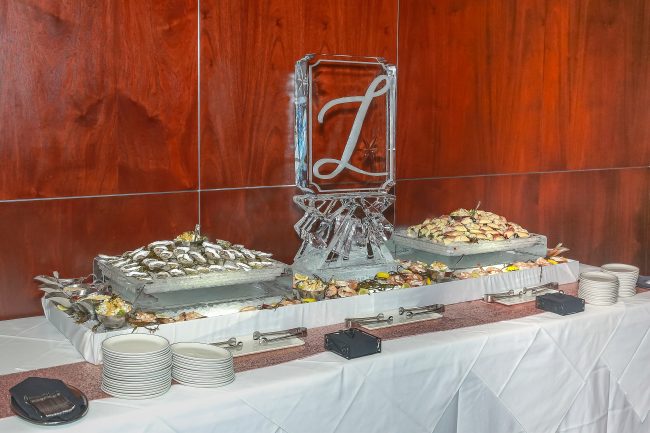 picture of Truluck's Woodlands private dining seafood display with large L monogram in ice. Seafood display includes fresh crab claws, oysters and cocktail shrimp.