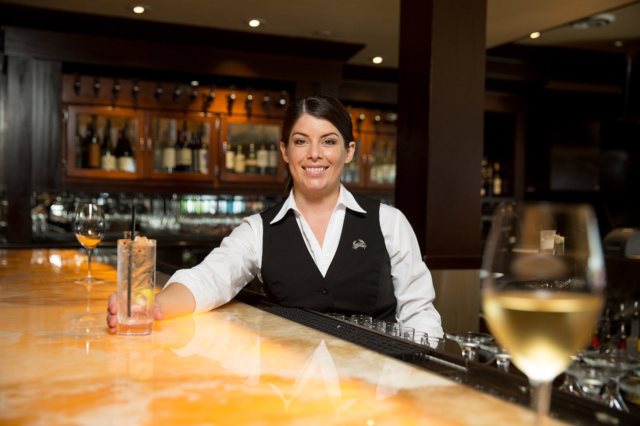 picture of Truluck's bar tender smiles while serving a cocktail