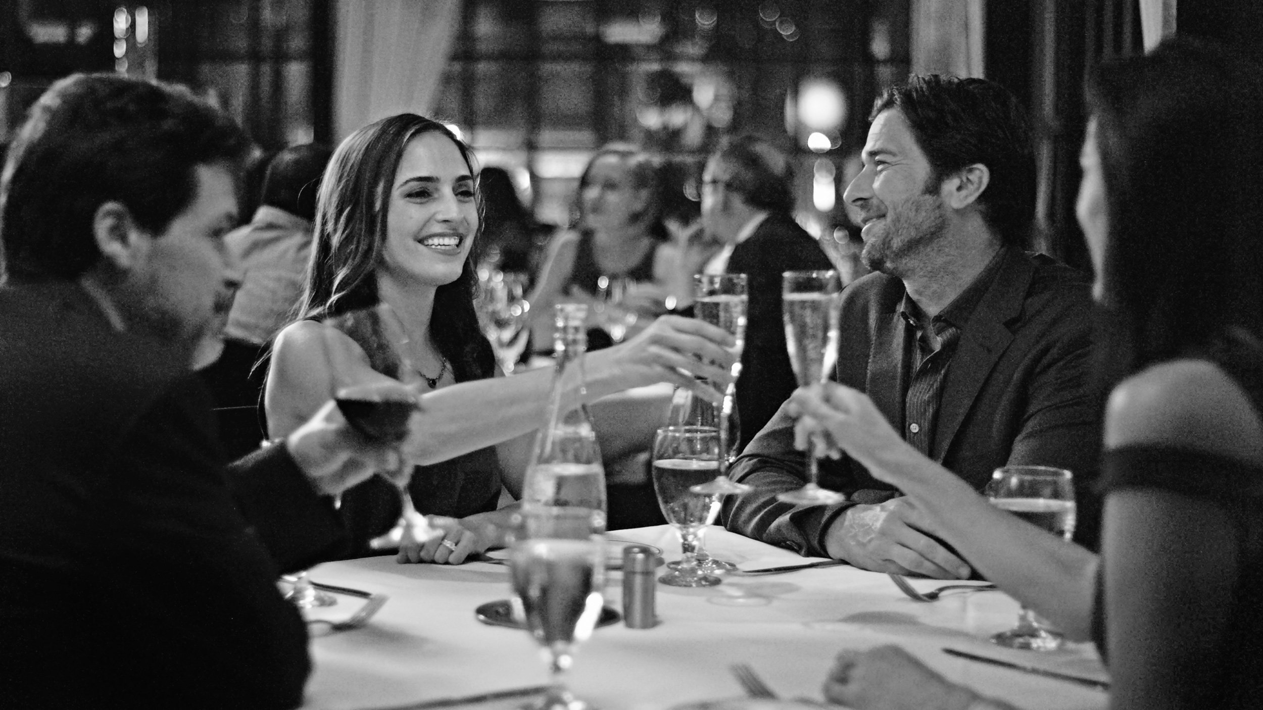 picture of A party of four smiles and toasts with champagne across a table