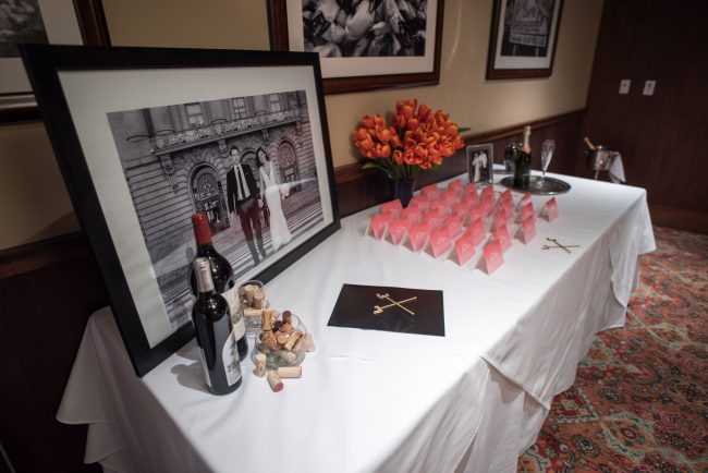 picture of Truluck's Dallas private dining room table display with photo of brde and groom and place cards. this table is dressed with wine bottles and a bouquet of orange tulips