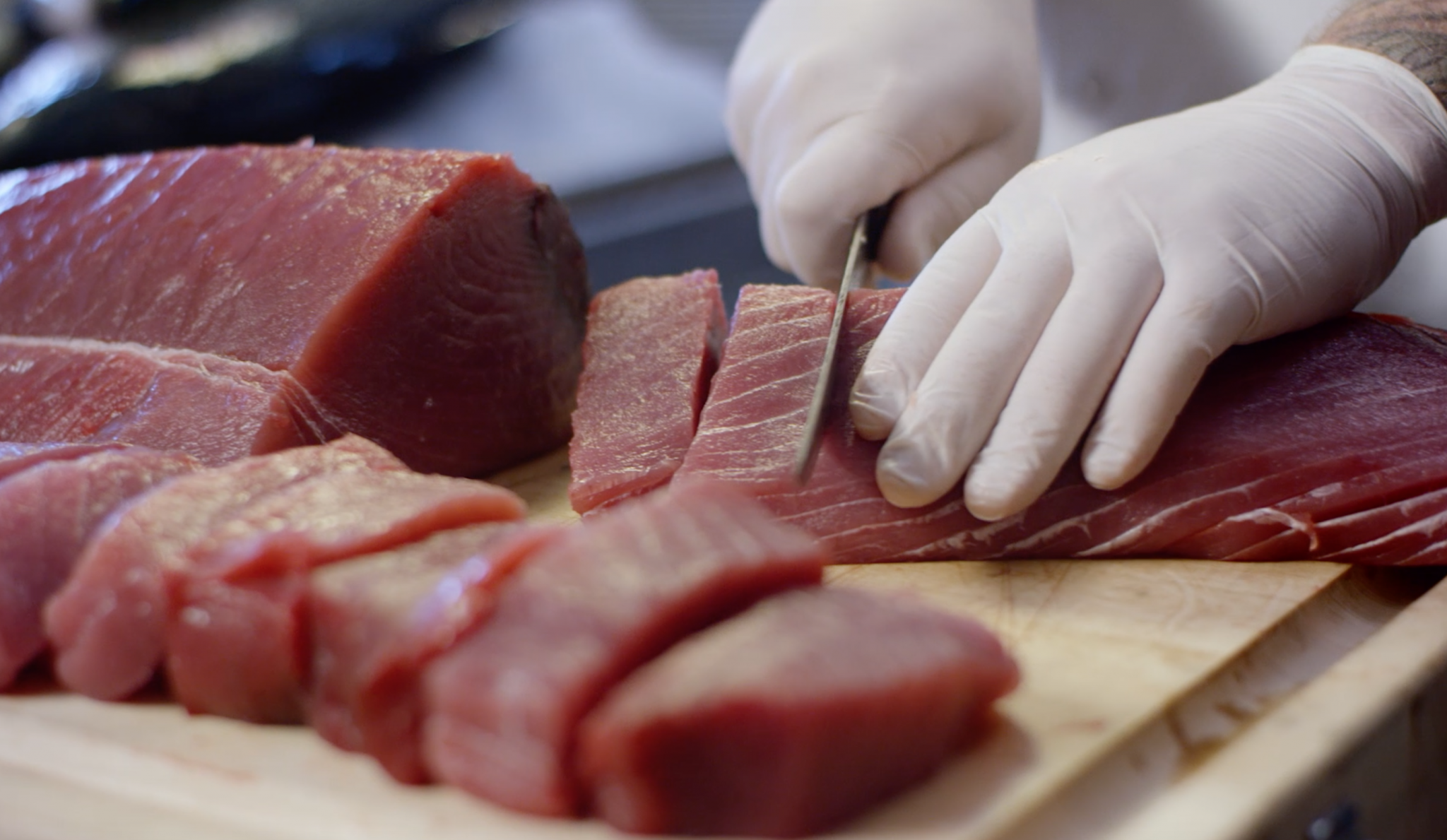 picture of Chef cutting fresh ahi tuna on a cutting board with gloved hands.