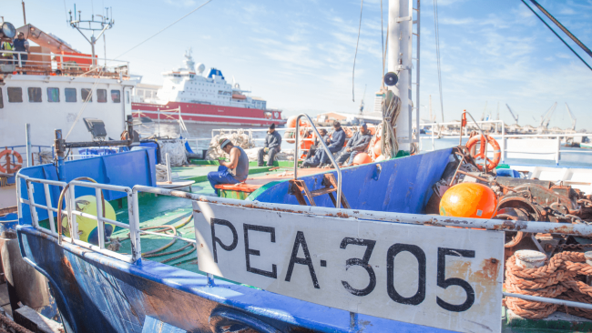 picture of a lobster fishing boat in the dock named PEA 305 with a few fishermen on board