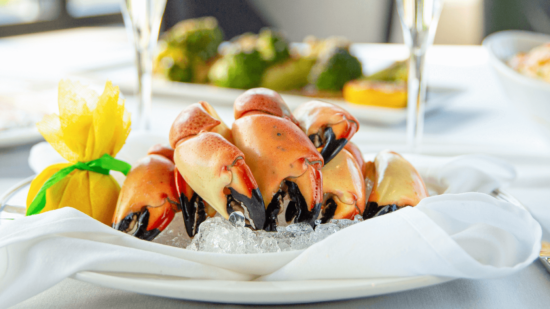 picture of seven Yucatan stone crab claws on a bed of ice with a lemon wrap